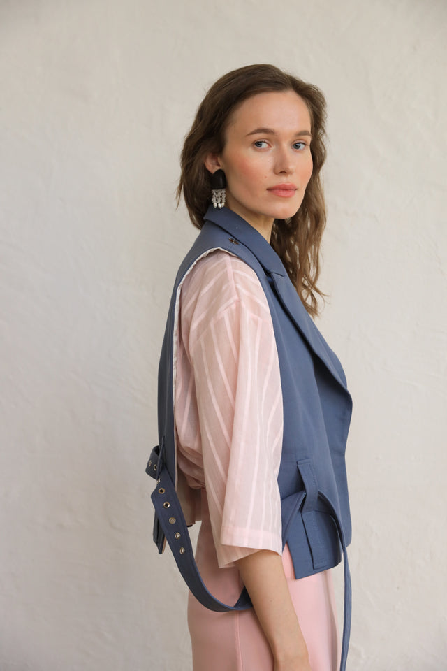 Woman wearing a blue vest over a pink shirt against a plain background